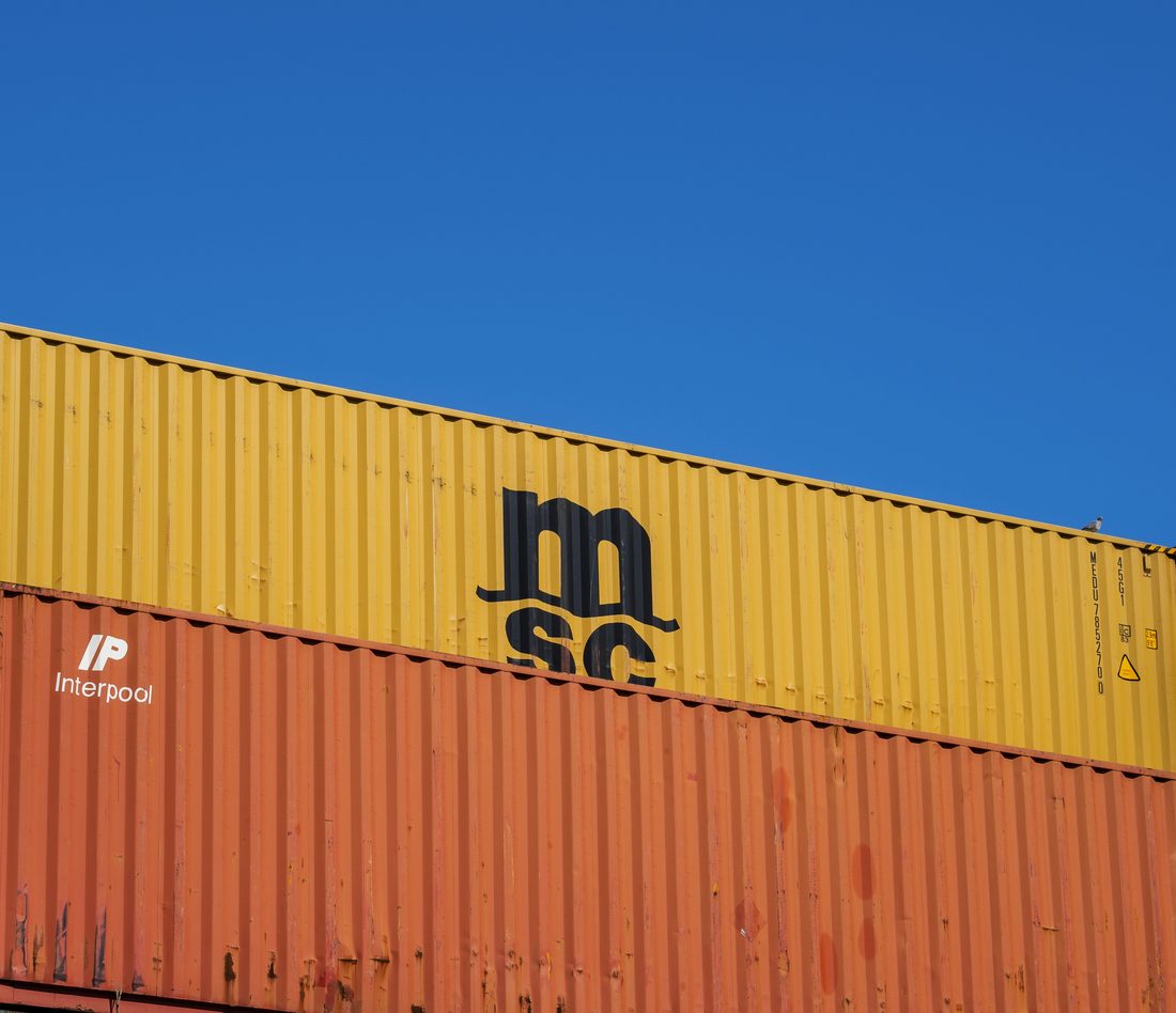 Stacked shipping containers against a clear blue sky